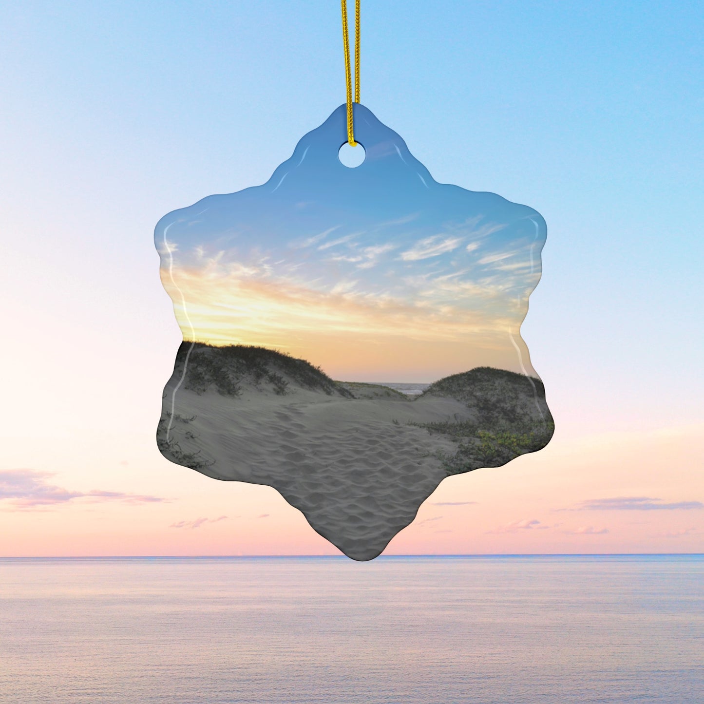 Ceramic holiday ornament featuring a landscape photograph of a California beach at sunset with rolling sand dunes, footprints, and gold-streaked clouds.