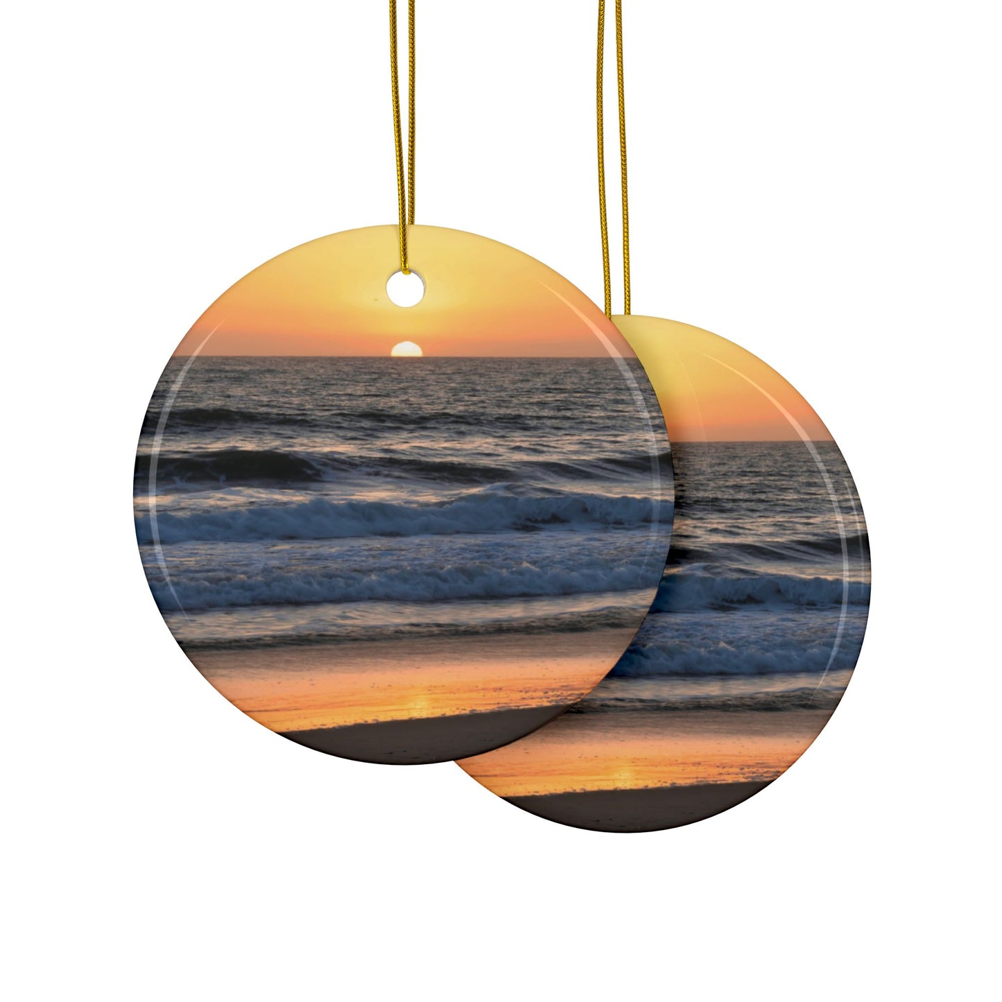 Front and back side of a ceramic Christmas ornament featuring a photograph of a vibrant amber and gold sunset over the Pacific Ocean with waves rolling toward the shore.
