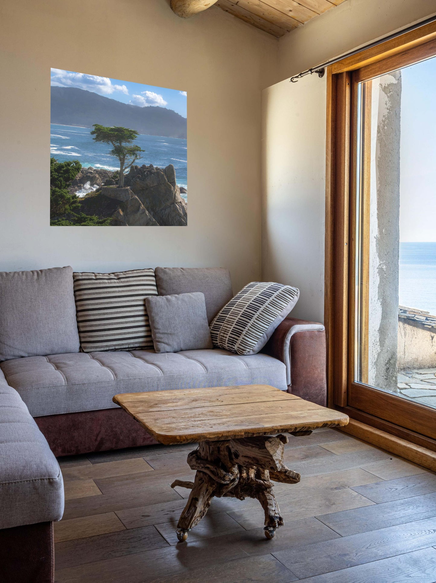 Living room with a gray sofa, wooden coffee table, and a canvas print of the lone cypress tree at Pebble Beach on a rocky cliff.