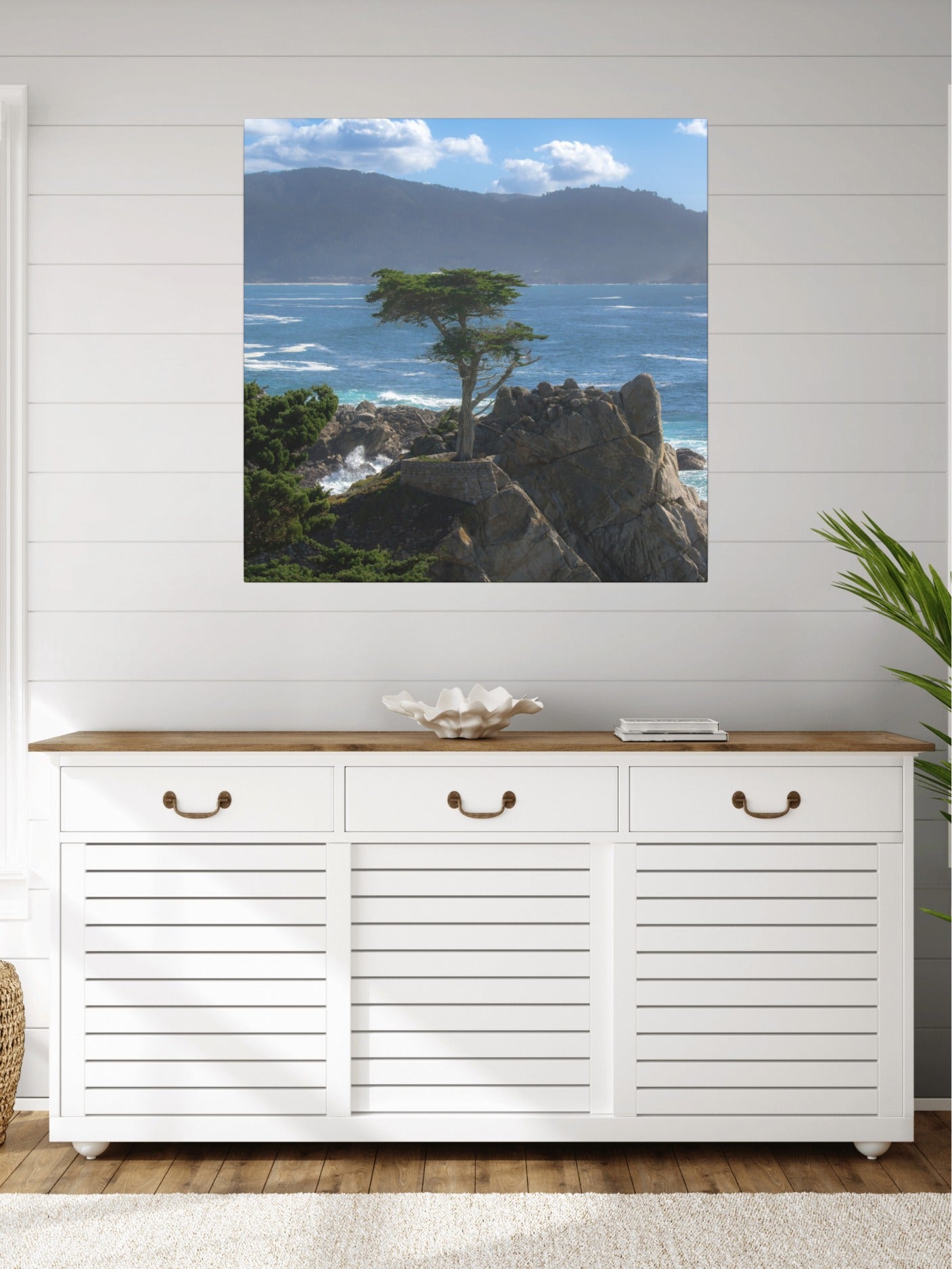 White storage cabinet with wooden top in a room with a canvas print of the lone cypress tree at Pebble Beach on a rocky cliff.