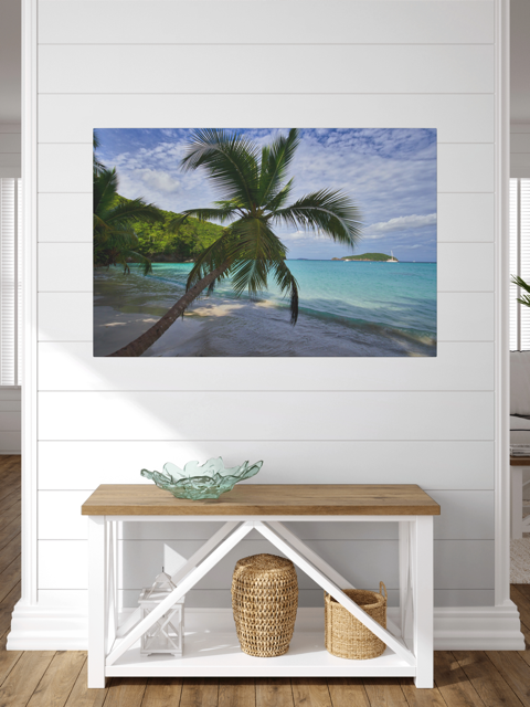 A canvas print of a tropical beach scene on a wall above a wooden bench with storage.