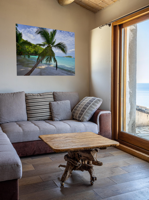 Living room with a gray sofa, wooden coffee table, and a canvas print of a tropical beach scene on the wall.
