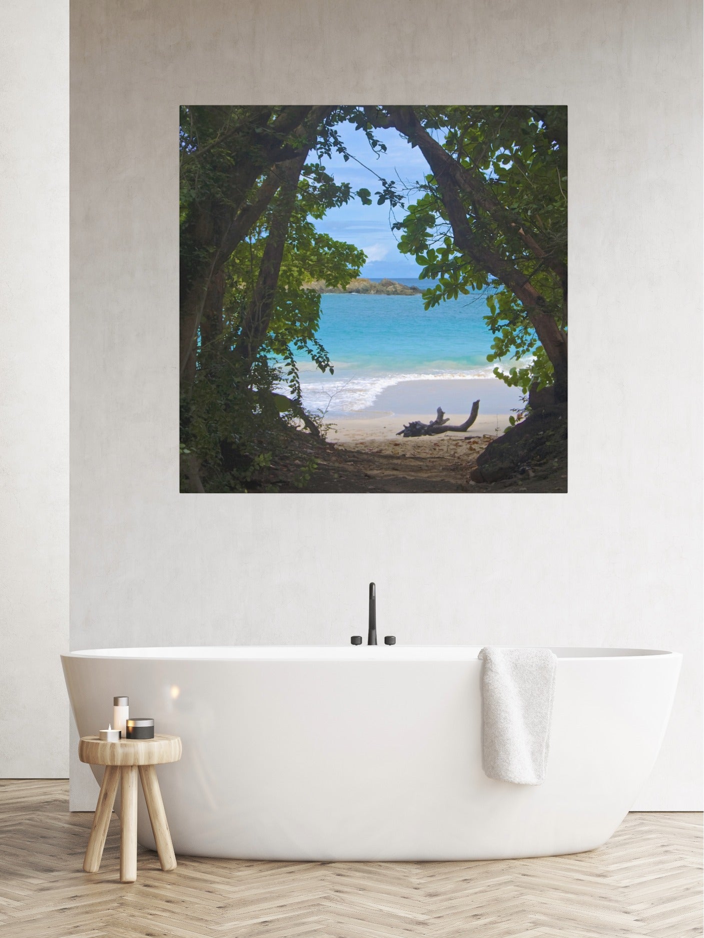 Tropical beach view through trees Hawaiian island canvas print on a wall above a white freestanding bathtub.