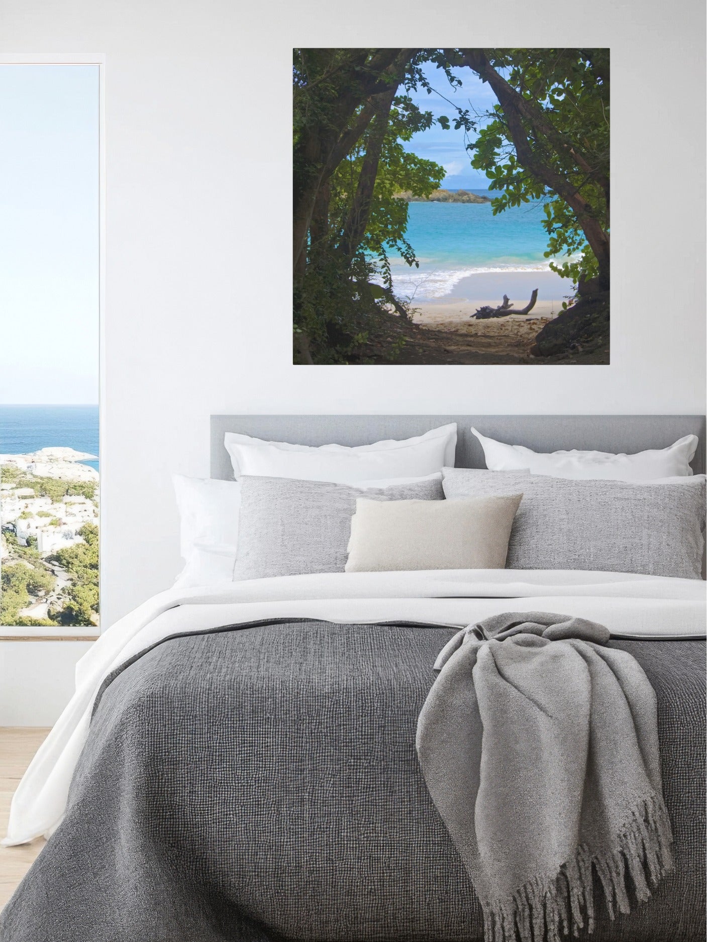 Tropical beach view through trees Hawaiian island canvas print above a bed with gray bedding and white pillows.