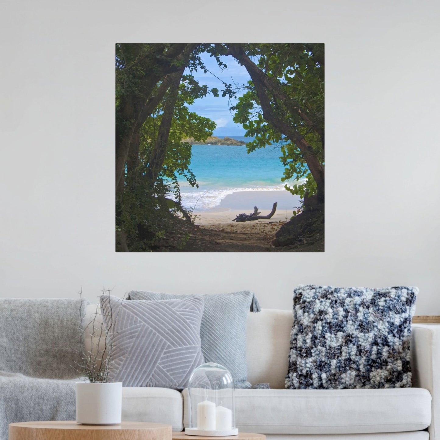 Tropical beach view through trees Hawaiian island canvas print on a wall above a sofa.