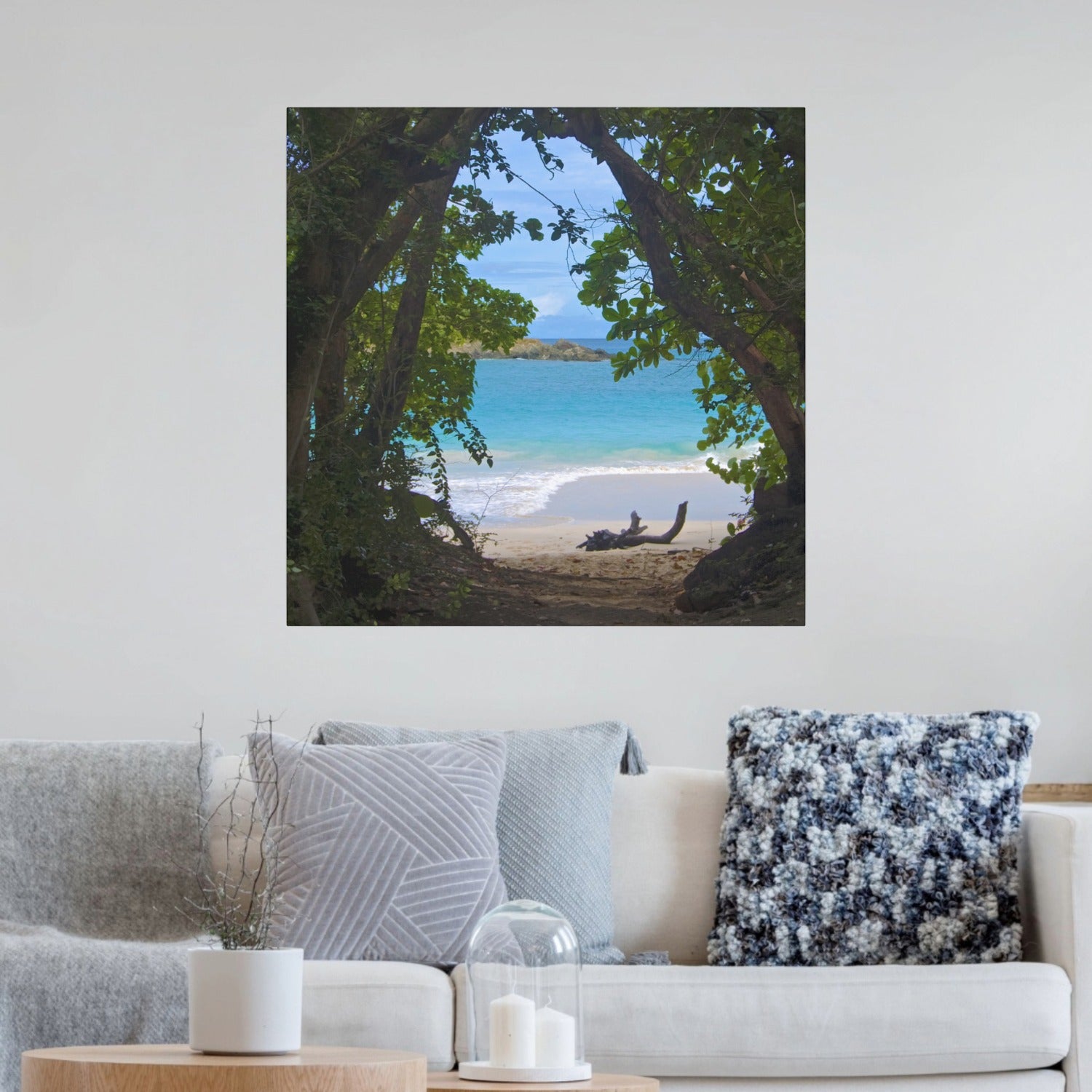 Tropical beach view through trees Hawaiian island canvas print on a wall above a sofa.