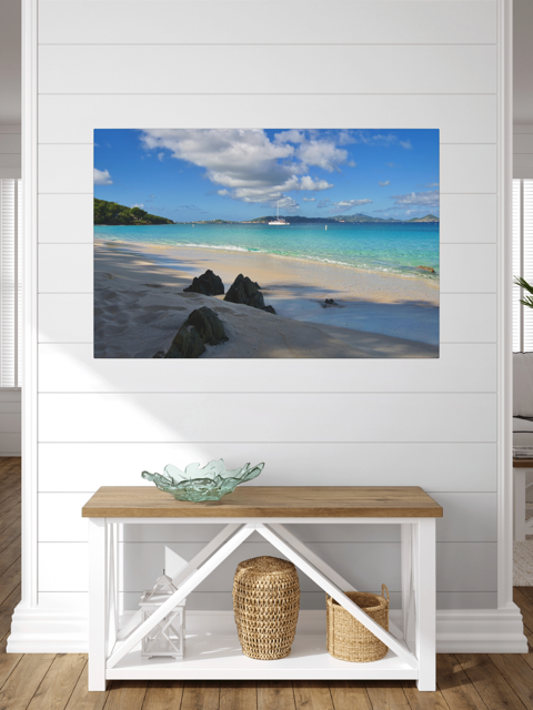 A canvas print of a tropical beach scene on a wall above a wooden bench with storage.