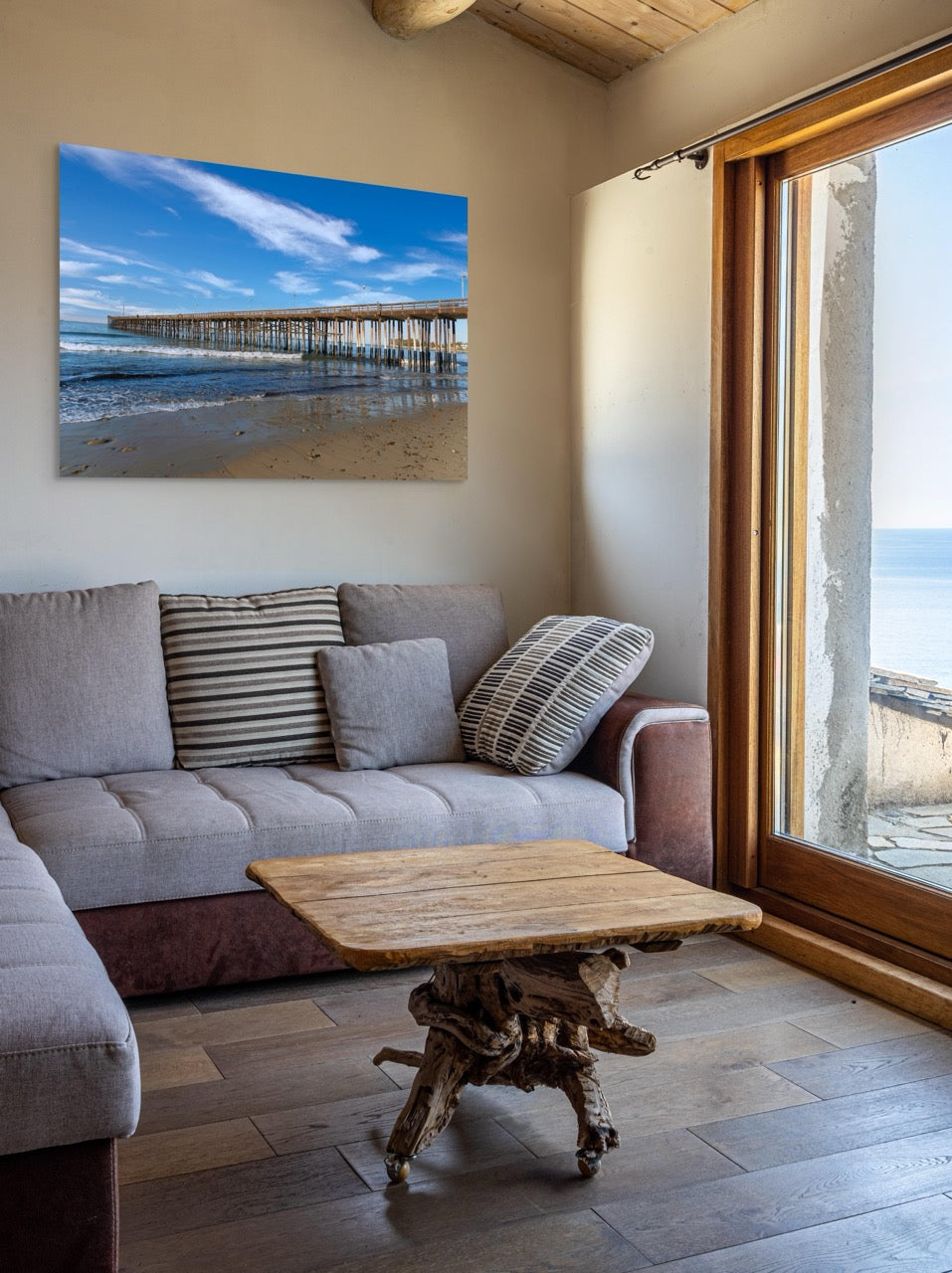 Living room with a gray sofa, wooden coffee table, and a large canvas print of Ventura Pier in California on the wall.
