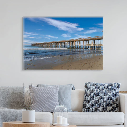 Canvas print of Ventura Pier in California on wall above a living room sofa with decorative pillows.