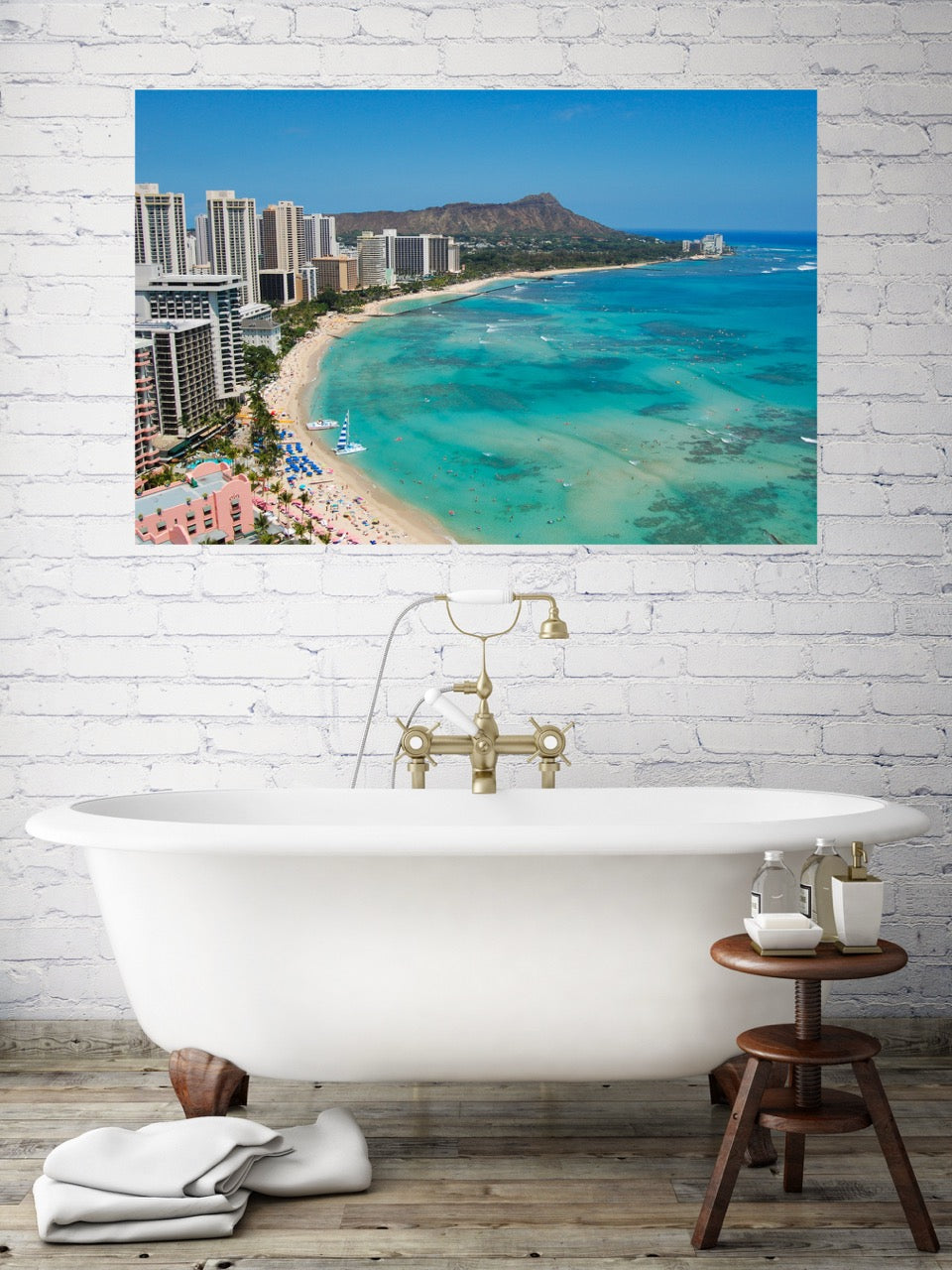 Bathroom wall above a tub with a large canvas print of an overhead view of the beach and hotels on Waikiki Beach in Hawaii with Diamond Head in the background.
