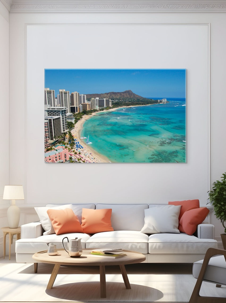 Large canvas print of an overhead view of the beach and hotels on Waikiki Beach in Hawaii with Diamond Head in the background above a white sofa with colorful cushions.