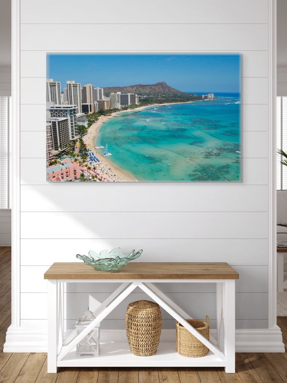 Canvas print of an overhead view of the beach and hotels on Waikiki Beach in Hawaii with Diamond Head in the background on a white wall above a wooden bench.
