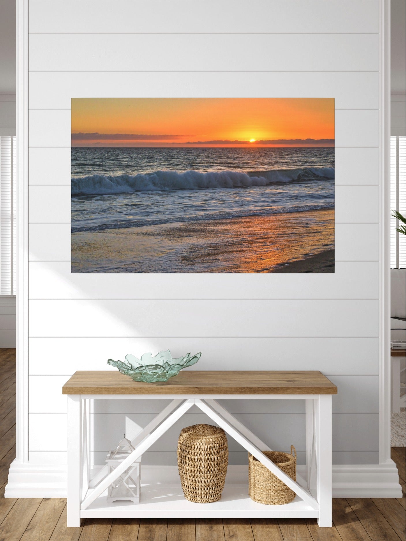 Canvas print of a Zuma Beach sunset in Malibu California with golden sky and reflective sand on a wall above a wooden bench with white shelves.
