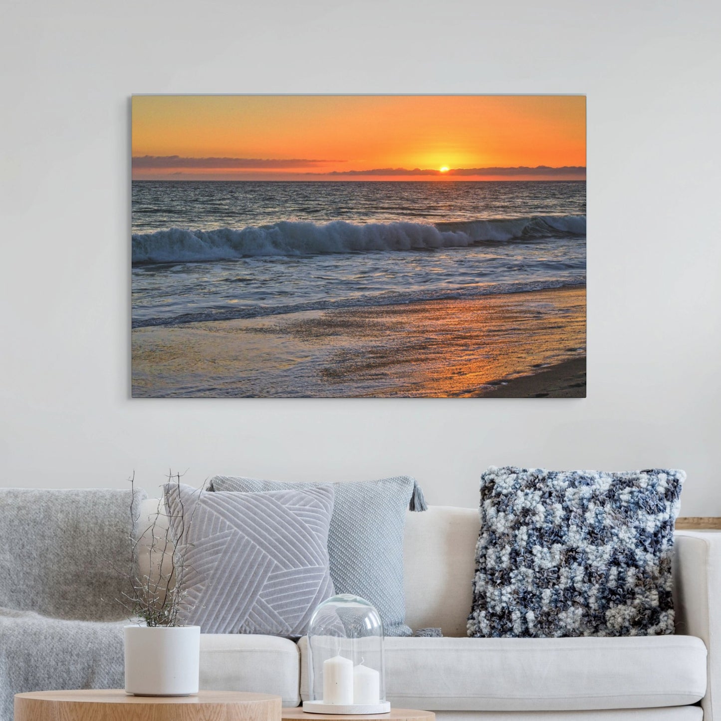 Canvas print of a Zuma Beach sunset in Malibu California with golden sky and reflective sand hanging on a wall above a sofa.