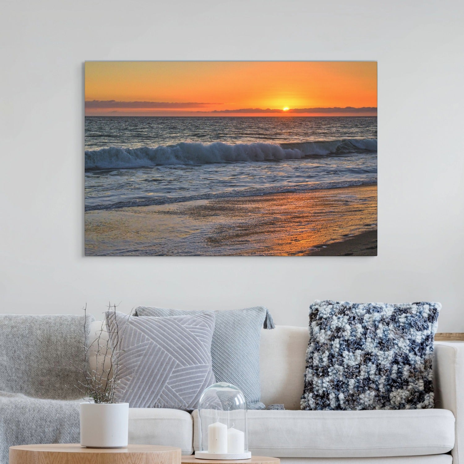 Canvas print of a Zuma Beach sunset in Malibu California with golden sky and reflective sand hanging on a wall above a sofa.